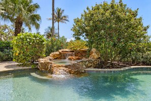 A clear pool with a waterfall feature surrounded by lush greenery and palm trees. - 5 Bedroom / 5 Bath Luxury Estate (Captiva)
