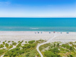 A beach with a clear view of the ocean, a sandy path, and several umbrellas. - 5 Bedroom / 5 Bath Luxury Estate (Captiva)