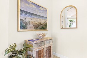 Ein Zimmer mit einem Strandbild, einem Spiegel und einer Holzkabine mit Dekorationen.