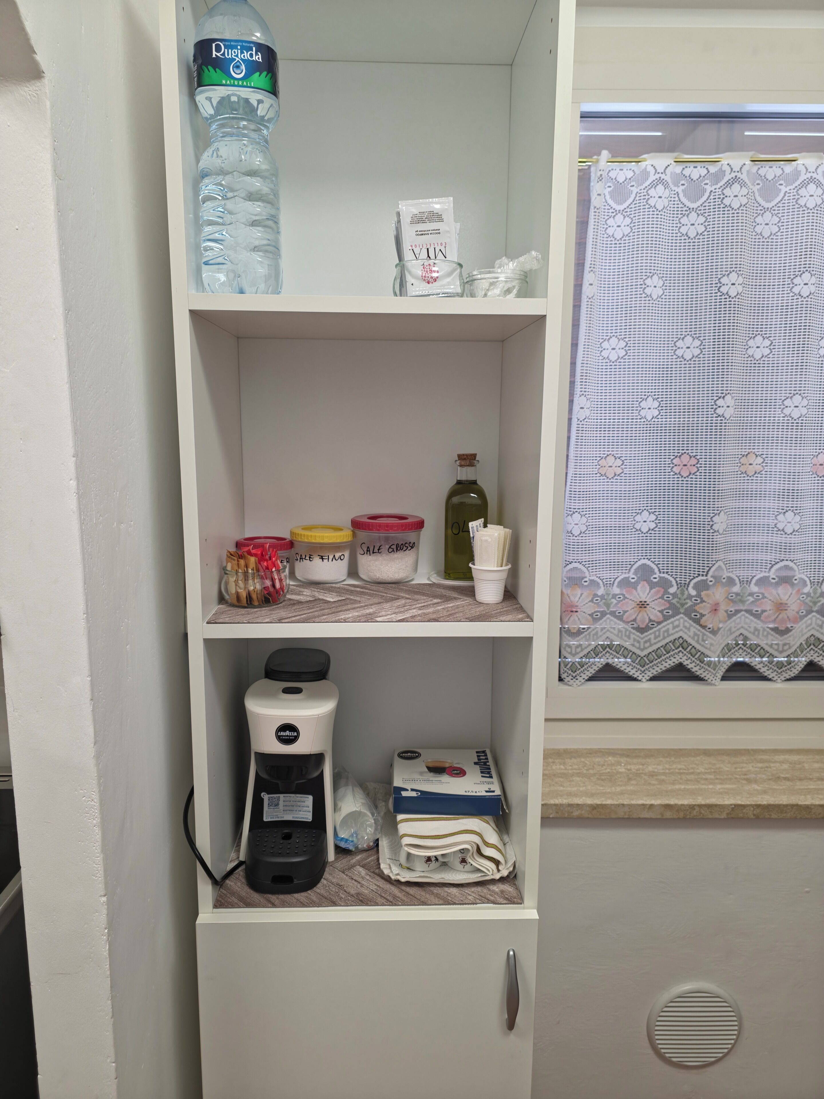 Un armario de cocina con una cafetera, una botella de agua y diversos utensilios de cocina.