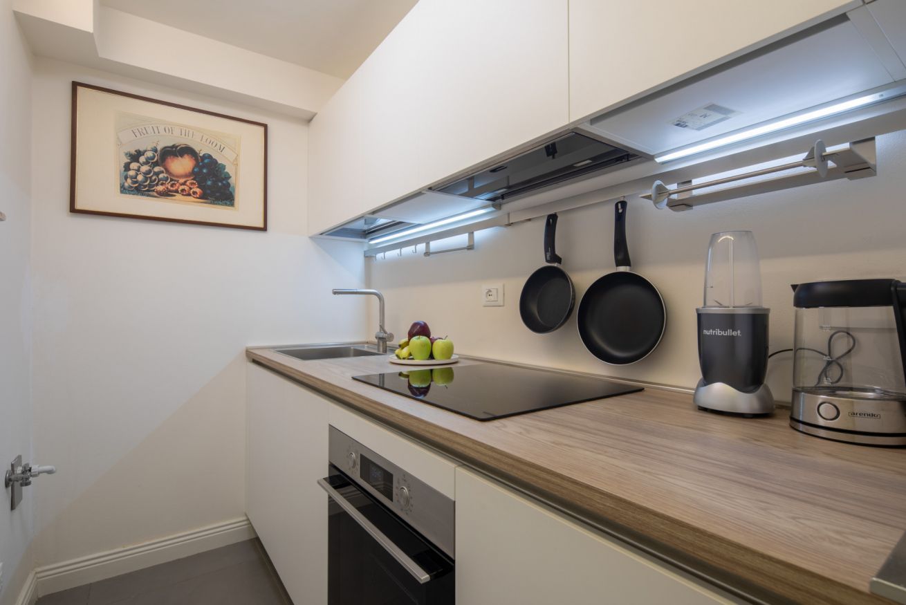 Uma cozinha moderna com forno embutido, fogão, liquidificador e um quadro na parede.