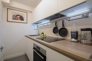 A modern kitchen with a built-in oven, a stovetop, a blender, and a framed picture on the wall. - Oltrarno Secret Nest (Florence)