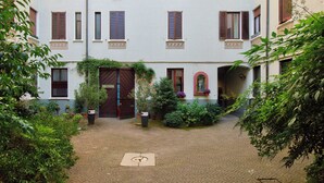 A courtyard with a cobblestone path, a central door, and surrounding greenery. - Isola Stay - A beautiful little nest in Isola, in the heart of Milan (Milano)