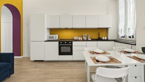A modern kitchen with white cabinets, a black oven, and a yellow backsplash. - Isola Stay - A beautiful little nest in Isola, in the heart of Milan (Milano)