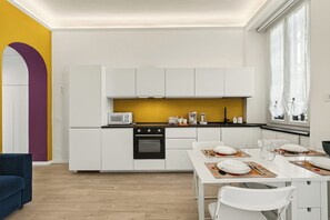 A modern kitchen with white cabinets, a black oven, and a yellow backsplash. - Isola Stay - A beautiful little nest in Isola, in the heart of Milan (Milano)