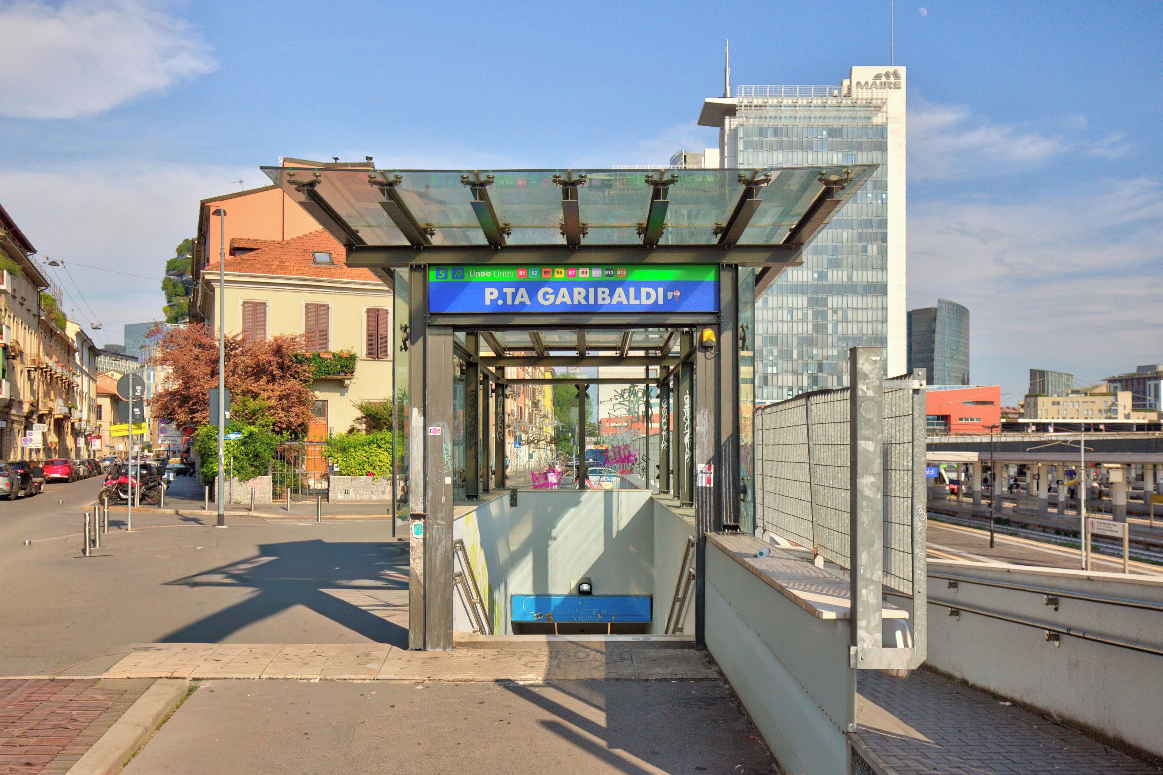 Eine Bushaltestelle mit einem Schild für P.T.A. Garibaldi, eine Stadtstraße mit parkenden Autos und Gebäuden im Hintergrund.
