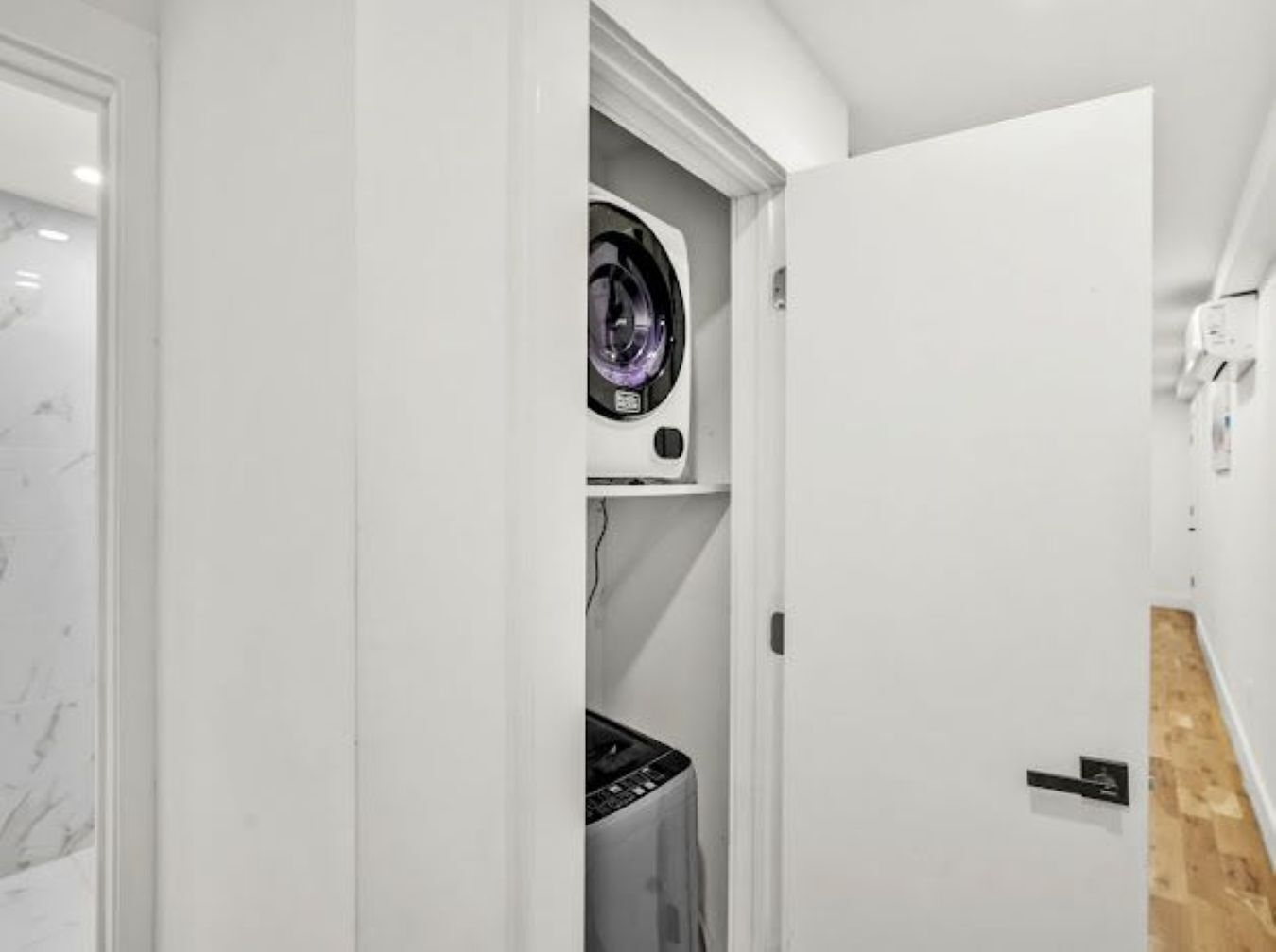Une buanderie équipée d’un lave-linge, d’un sèche-linge et d’une porte donnant sur une autre pièce.
