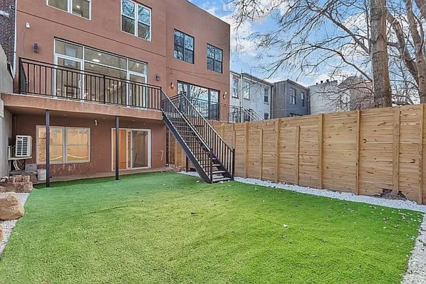 Un bâtiment moderne à deux étages, doté d’un balcon, d’une clôture en bois et d’une pelouse bien entretenue.