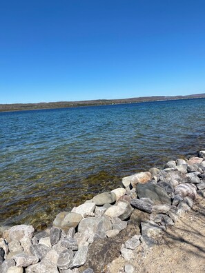 En klar sjö med en stenig strand och kullar i fjärran.