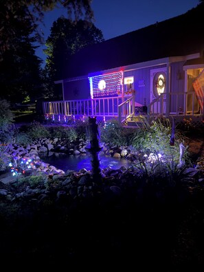 A house with a deck, a pond, and decorative lights. - Charming 3-bedroom house with in Boyne City (Boyne City)