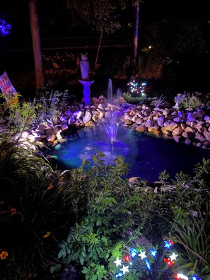 A nighttime garden with a fountain, illuminated rocks, and decorative lights. - Charming 3-bedroom house with in Boyne City (Boyne City)
