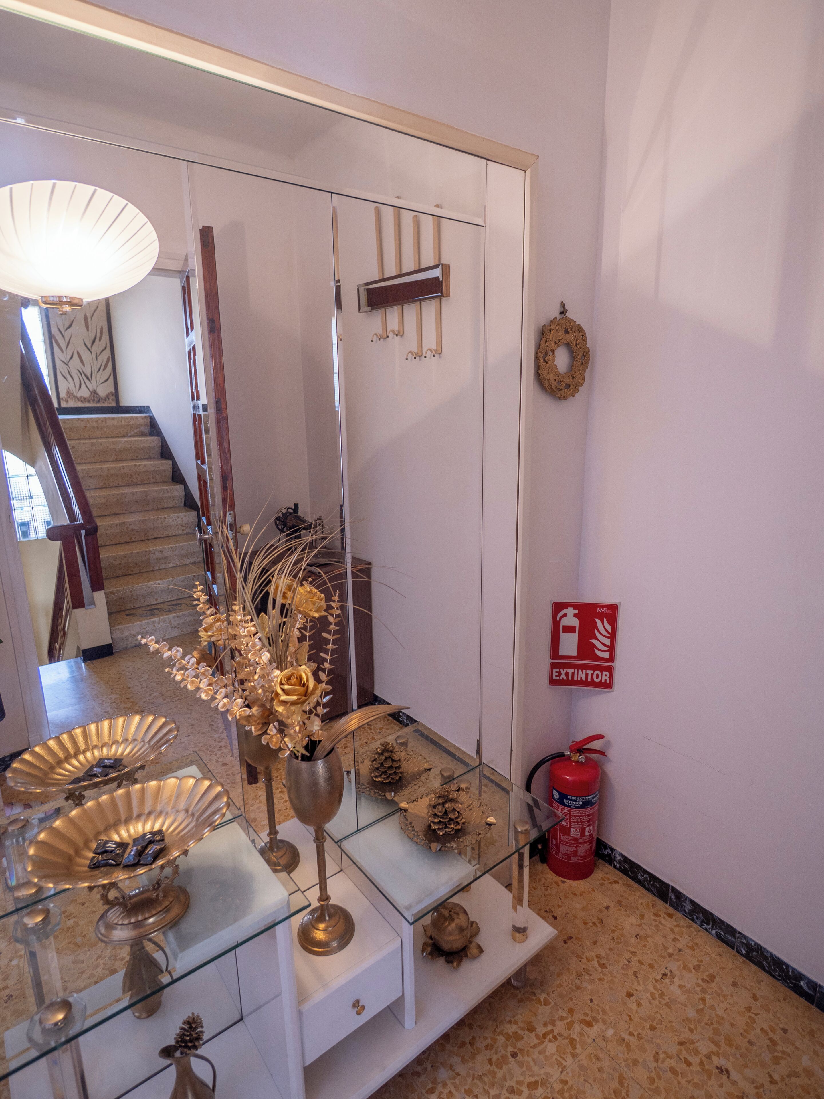 A hallway with a glass display table, a fire extinguisher, and a staircase.