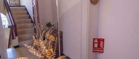 A hallway with a glass display table, a fire extinguisher, and a staircase.