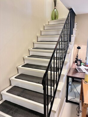 Eine Treppe mit schwarzen Geländern, weißen Stufen und einer grünen Vase am oberen Ende.