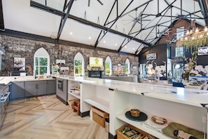 A spacious kitchen with a long island, wooden flooring, and exposed brick walls.