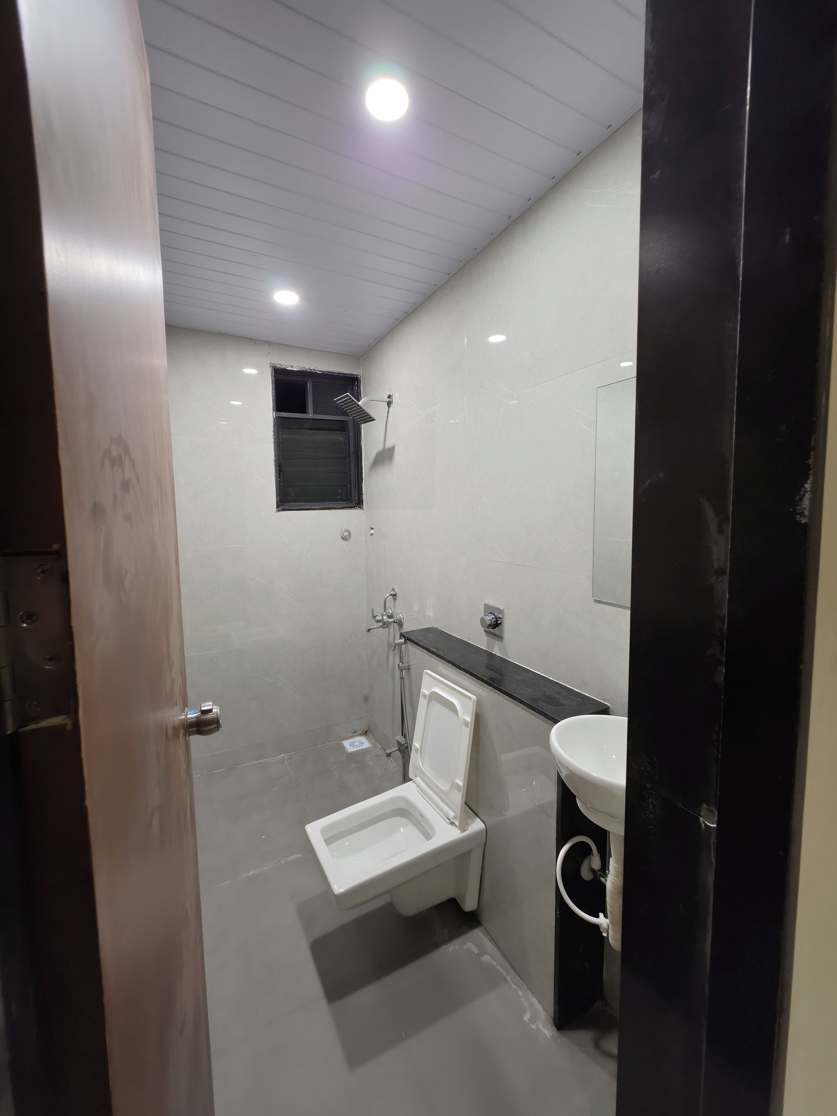 A small, modern bathroom with a toilet, sink, and shower.