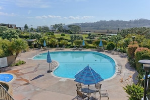 A swimming pool with lounge chairs and umbrellas, surrounded by landscaped gardens and a view of distant hills. - Del Mar Daze - Pet Friendly with AC in Del Mar with Ocean Views (Del Mar)