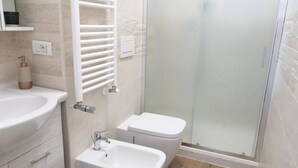A modern bathroom with a sink, bidet, and glass shower enclosure. - IMB23 • Central Apartment in Milan • (Milano)