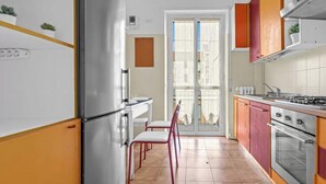 Een keuken met een koelkast, fornuis en stoelen.