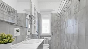 Een moderne badkamer met een dubbele wastafel, toilet en een douchegedeelte.