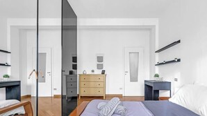 Een moderne slaapkamer met een bed, nachtkastjes, een dressoir en een spiegel.