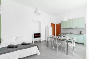 A modern room with a bed, a dining table with chairs, a TV, and a kitchenette. - VE2 [Island] Cool Apartment • Exclusive • (Milano)