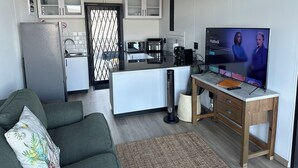Um espaço compacto com cozinha compacta, sofá, televisão e uma pequena mesa.
