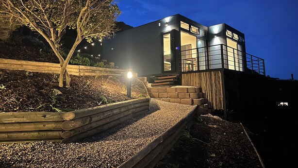 Um edifício moderno com um deck de madeira, uma escadaria e uma entrada bem iluminada.