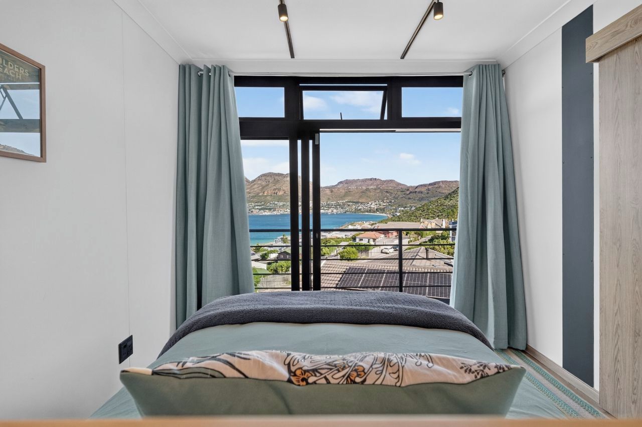 A bedroom with a large bed, a view of the sea, and a balcony with solar panels.