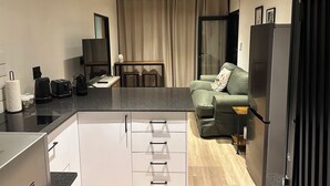 Um espaço compacto com cozinha compacta, área de refeições e sala de estar com sofá e mesa de centro.