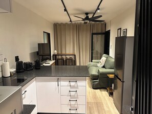 A compact living space with a kitchenette, a dining area, and a seating area with a sofa and a coffee table. - Couples cosy 1-bedroom cottage with stunning view over Simonstown Bay (Cape Town)