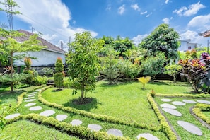 Ein gepflegter Garten mit einem Kiesweg, verschiedenen Pflanzen und einem weißen Gebäude im Hintergrund.