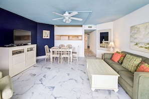 A living room with a TV, dining table, chairs, a sofa, and a ceiling fan. - Includes Xplorie Activities & Linens. PYRAMID-1BR OF condo w/outdoor pool. (Ocean City)