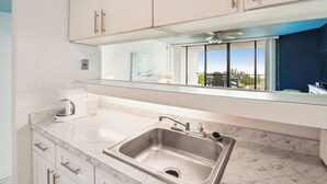 A modern kitchen with a stainless steel sink, white cabinets, and a large window offering a view of the outdoors. - Includes Xplorie Activities & Linens. PYRAMID-1BR OF condo w/outdoor pool. (Ocean City)
