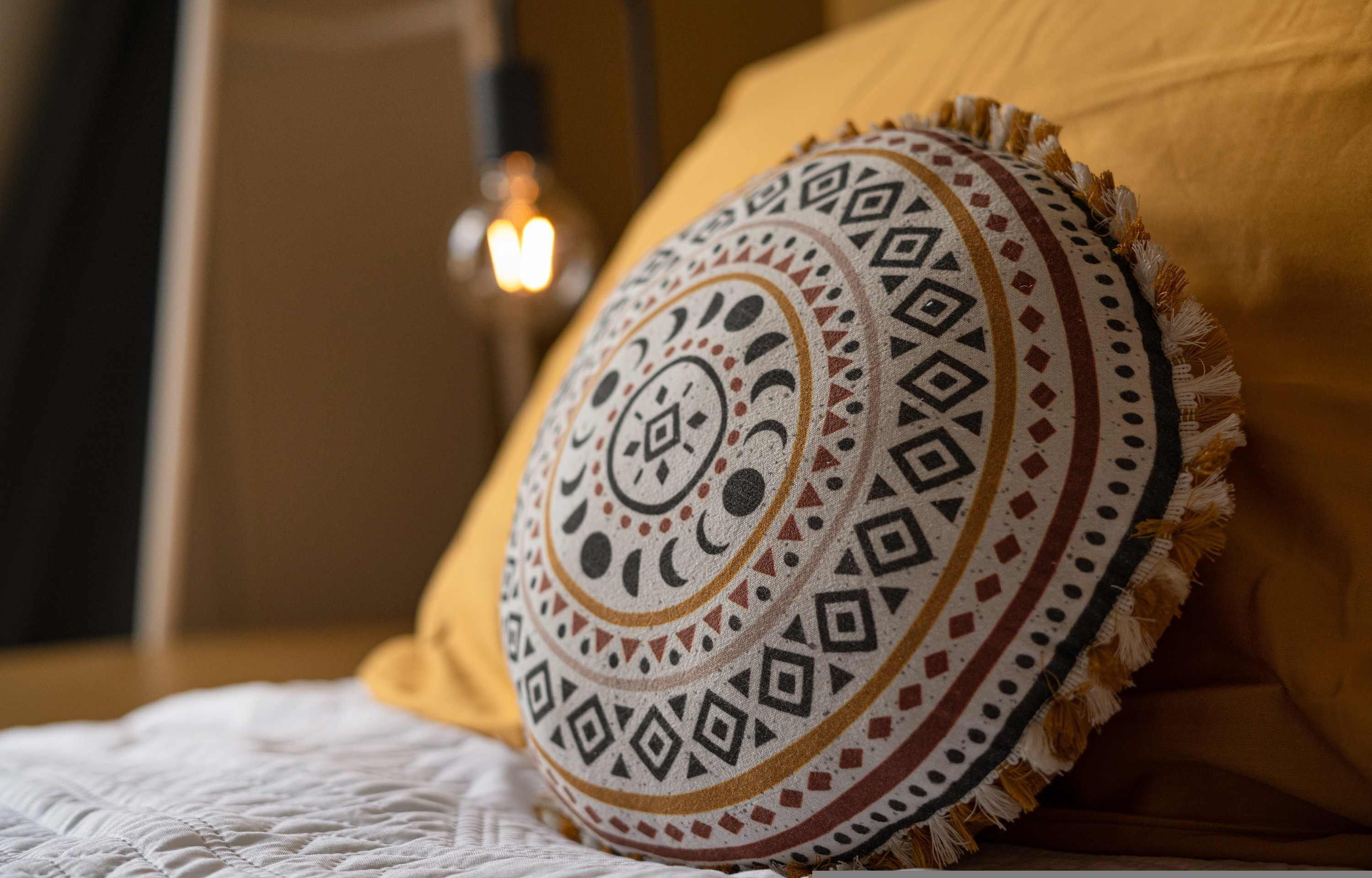 A bed with a patterned pillow and a white quilt.