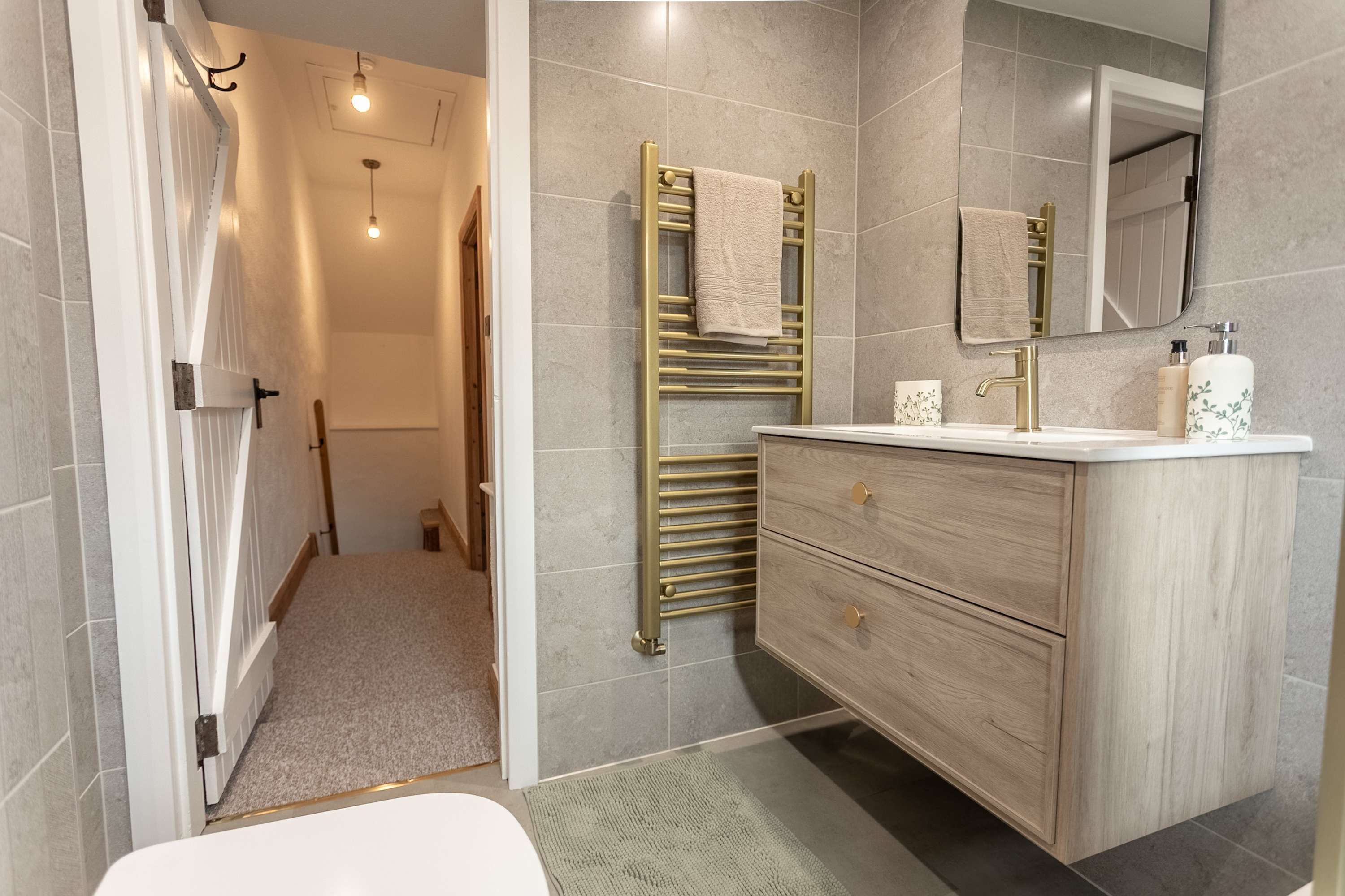 Un baño moderno con tocador de madera, toallero y espejo.