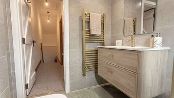 Un baño moderno con tocador de madera, toallero y espejo.