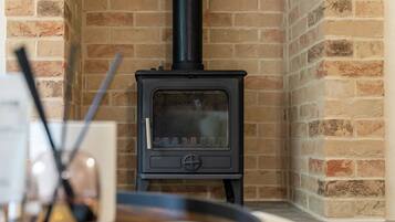 A black wood-burning stove in a corner with a brick wall.