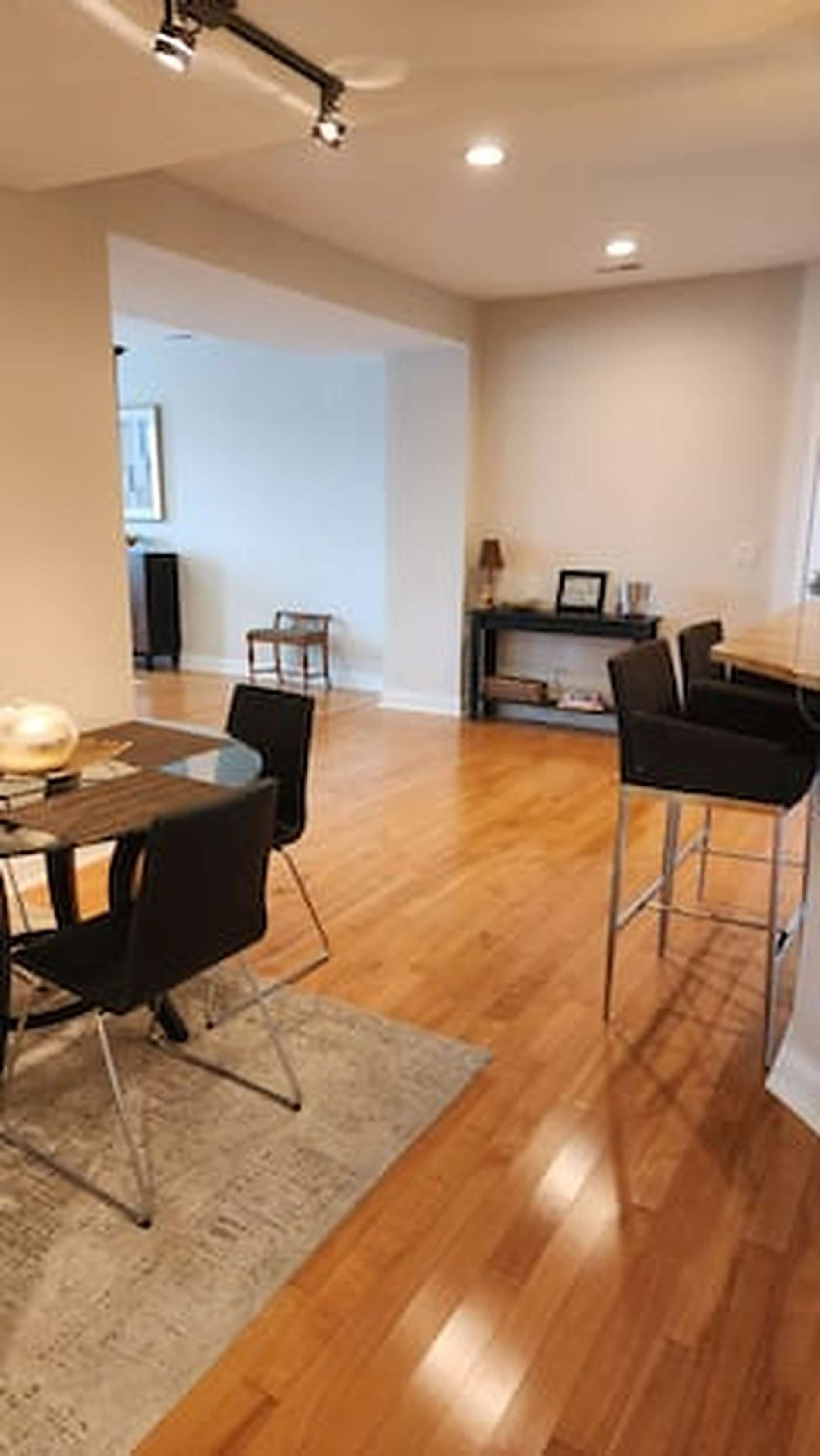 An open-plan living area with a dining table, chairs, and a kitchen area.