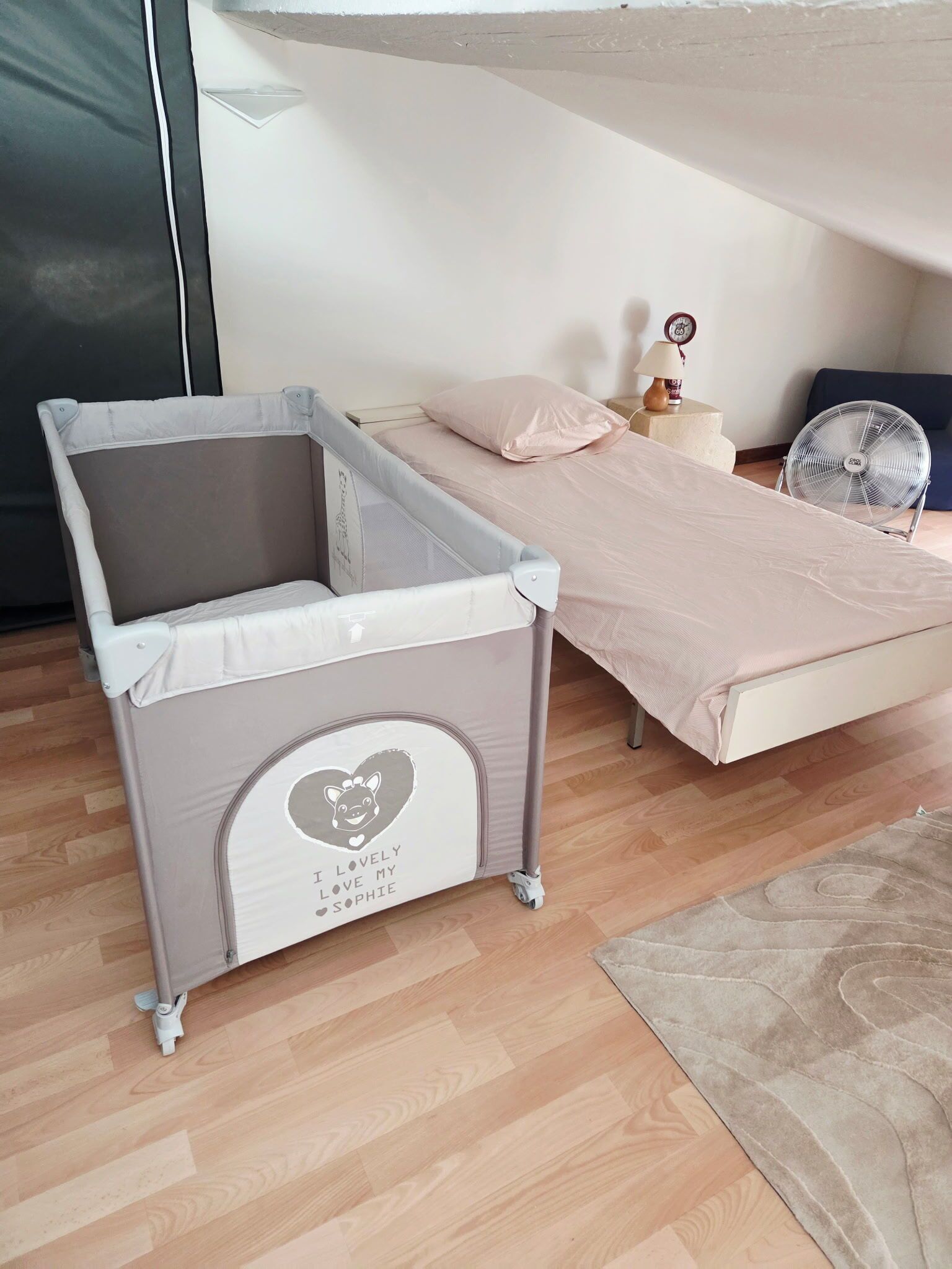 Una cama litera infantil con dosel, una mesita de noche pequeña con lámpara y un reloj decorativo.
