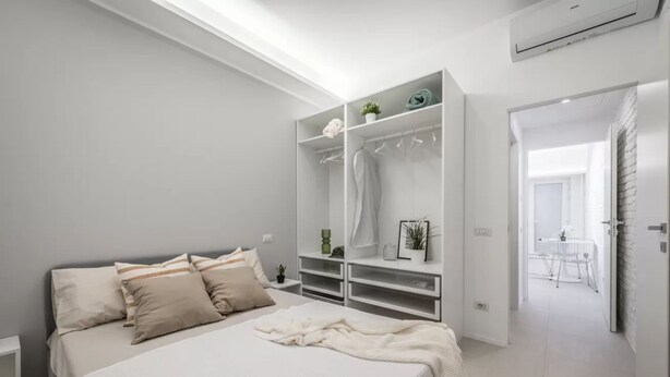 Un dormitorio con cama, vestidor y vista a un comedor.
