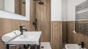 Un baño moderno con un lavamanos blanco, grifo negro y una ducha con pared de madera.
