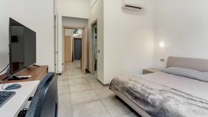 Ett sovrum med en säng, ett skrivbord med en dator, en tv och en luftkonditioneringsanläggning.