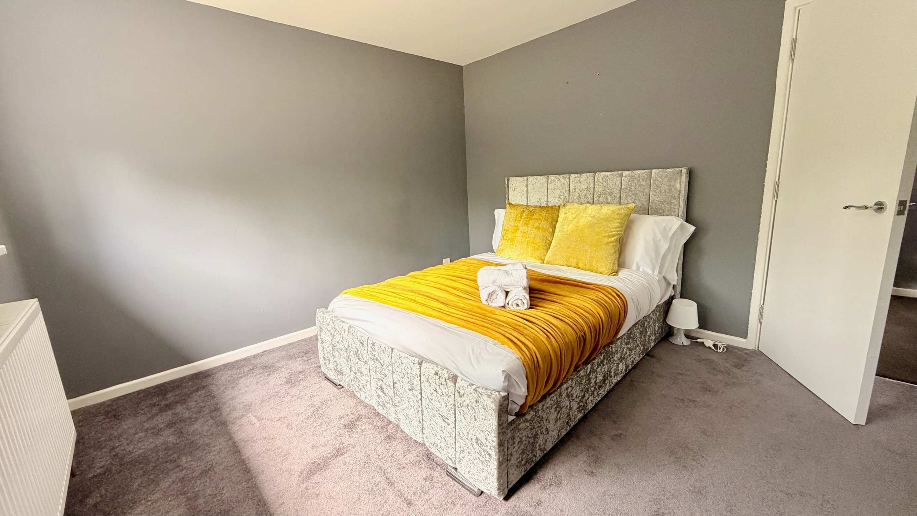 A bedroom with a bed, a nightstand, and a door.