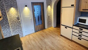 Eine Küche mit Holzschränken, einer Mikrowelle und einer Tür mit Licht.