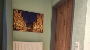 Ein Zimmer mit Holzboden, einem weißen Heizkörper, einer Tür und einem Stadtbild an der Wand.
