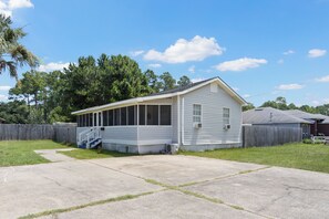 A single-story house with a covered porch, a front yard, and a wooden fence.