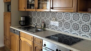 Una cocina con armarios de madera, estufa integrada y salpicadero de azulejos.