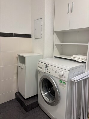 A compact laundry room with a Bosch washing machine and dryer, a small cabinet, and a tiled wall. - Peaceful Farm Stay for Animal Lovers (Bopfingen)
