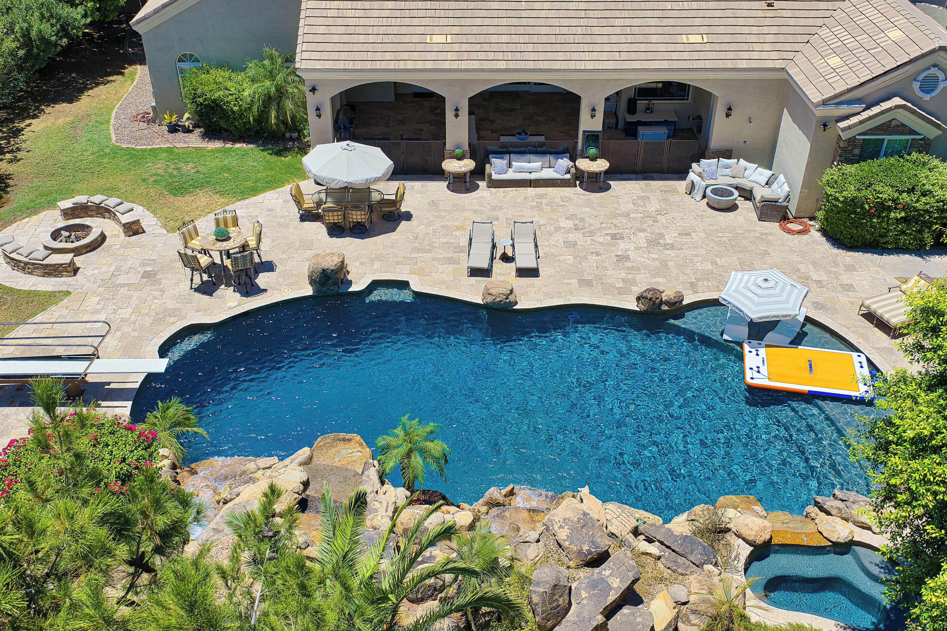 A pool area with a hot tub, lounge chairs, and a dining set.